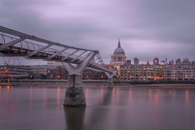 Bridge over river against sky in city