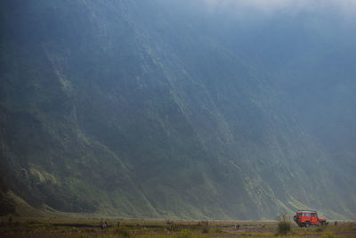 Off-road vehicle on landscape against mountains