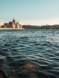 Hungarian parliament building by river against sky