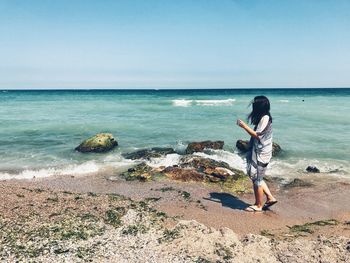 Full length of woman walking at beach against sky