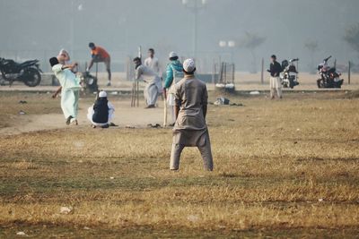 People playing cricket on field