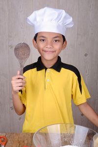 Boy wearing chef hat preparing food in kitchen at home