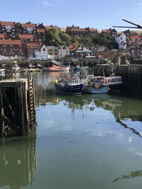 Boats moored in lake against buildings in city