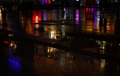 Reflection of illuminated buildings in puddle at night