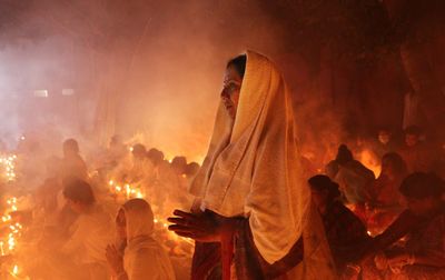 A women is standing inside croud of people where all are praying at rakher upobash