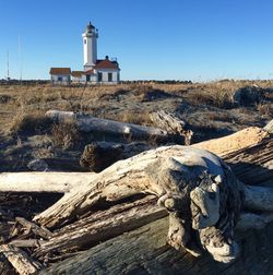 Lighthouse by building against clear blue sky