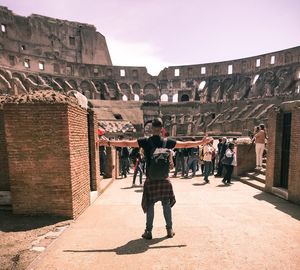 People walking in historic building against sky