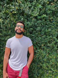 Young man standing against plants