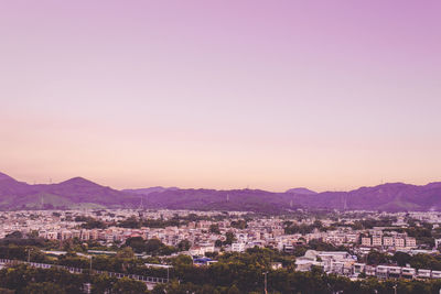 View of townscape by mountains against clear sky during sunset