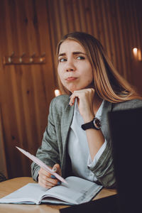 Young woman looking away while sitting on table