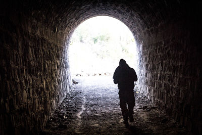 Rear view of silhouette man walking in tunnel