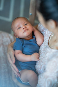 Portrait of cute baby boy lying on bed at home