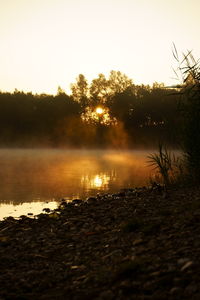 Scenic view of lake against sky at sunset