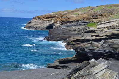 Rock formation on sea shore against sky