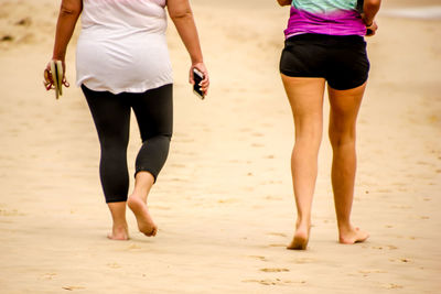 Low section of people walking on beach