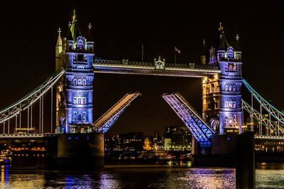 Illuminated bridge over river at night