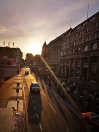 High angle view of people riding bicycles on city street during sunset