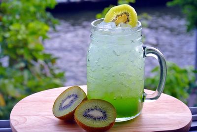 Close-up of kiwi with soda on wooden table