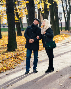 Couple with arm in arm standing on road at park during autumn