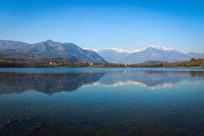 Scenic view of lake and mountains against clear blue sky