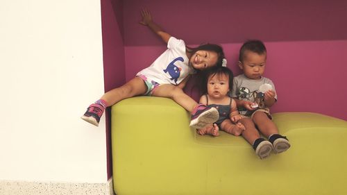 High angle view of siblings sitting on sofa