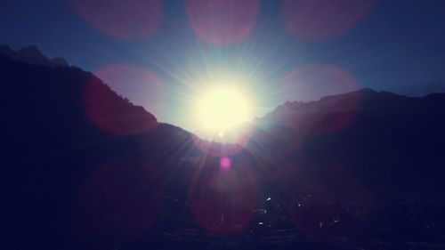 Sun shining through clouds over mountains