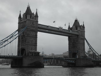 Tower bridge over river against cloudy sky