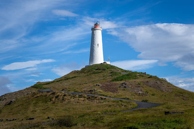 Lighthouse by mountain against sky