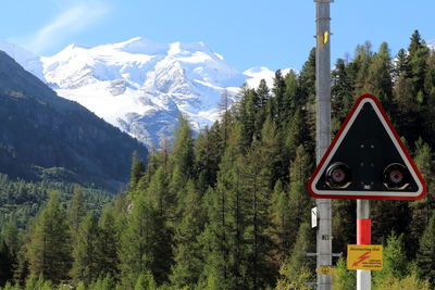 Information sign on snowcapped mountains against sky