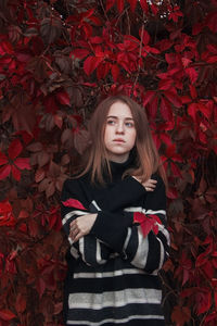 Portrait of young woman standing against plants