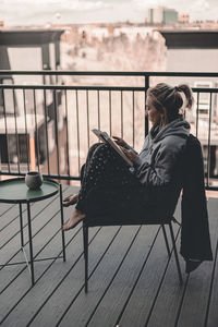 Side view of young woman sitting on bench