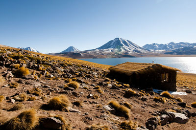 Scenic view of sea and mountains against clear blue sky