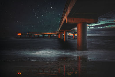 Bridge over sea against clear sky at night