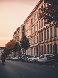 Cars on city street by buildings against sky