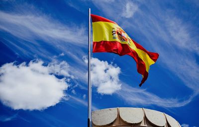 Low angle view of spanish flag waving against sky