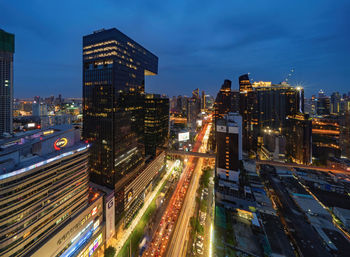 High angle view of illuminated street amidst buildings in city at night