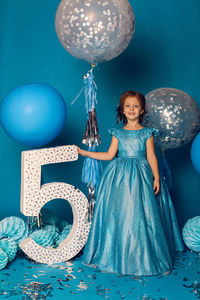 Girl in the blue dress in the studio with the balloon and with the number five