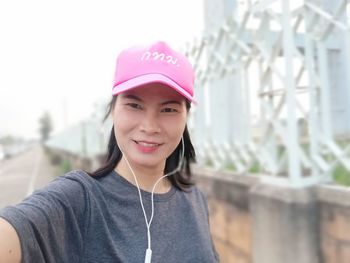 Portrait of smiling young woman wearing hat standing outdoors