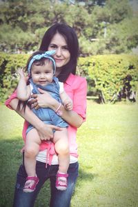 Portrait of mother carrying daughter in park