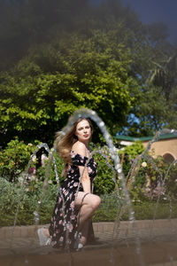 Portrait of young woman standing against trees