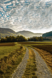 Road amidst field against sky