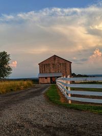 Road by building against sky during sunset