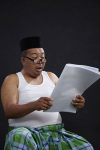 Midsection of man sitting on mobile phone while standing against black background