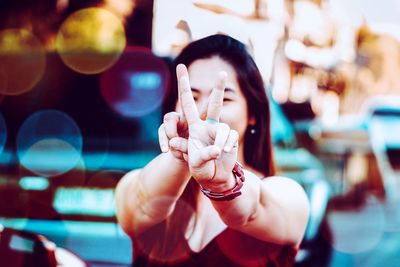 Woman gesturing peace signs while standing in city