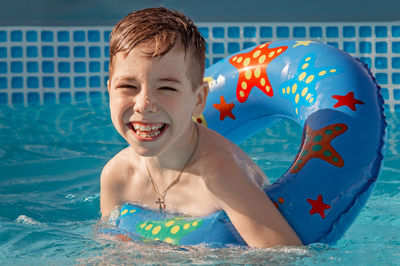 Smiling boy play and having fun in kiddie pool at summer sunny day. 