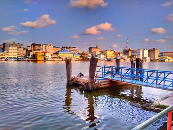 Scenic view of river by buildings against sky