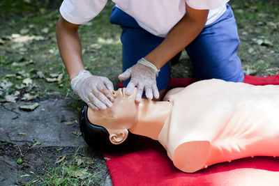 Low section of woman practicing on cpr dummy at field