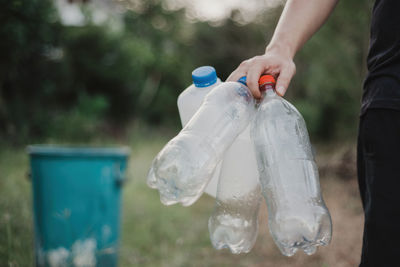 Low section of person cleaning garbage can