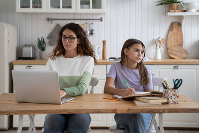 Young woman using laptop while sitting on table