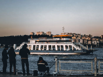 Rear view of people on boat in river against buildings